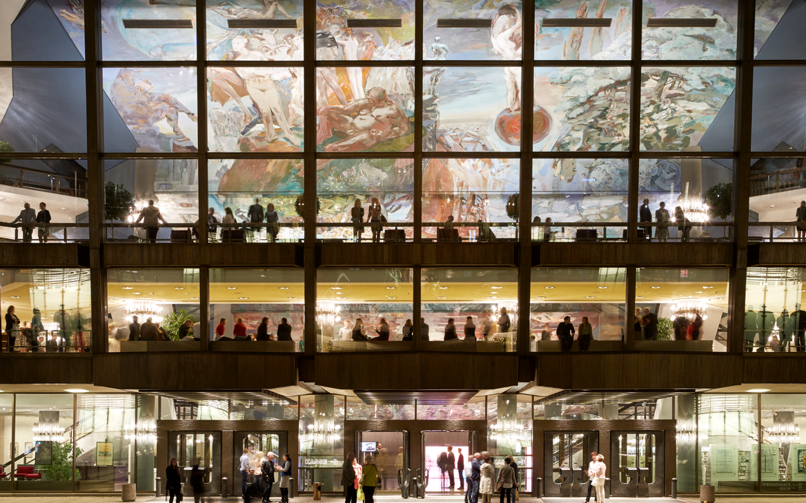 Die große Glasfassade des Leipziger Gewandhauses bei Nacht, innen beleuchtet mit Zuschauern auf den Foyerebenen