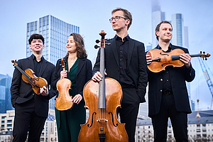 Das Foto zeigt das Eliot Quartett in Untersicht vor einer modernen Großstadt-Skyline