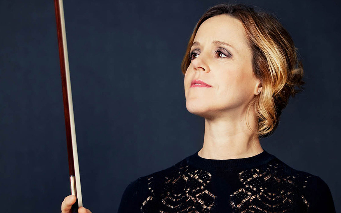 Das Foto zeigt die Cellistin Sol Gabetta, die mit erhobenen Bogen vor der Kamera steht und den Bogen betrachtet