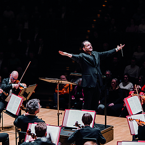 Gewandhauskapellmeister Andris Nelsons steht mit ausgebreiteten Armen vor dem Orchester
