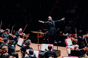Gewandhauskapellmeister Andris Nelsons steht mit ausgebreiteten Armen vor dem Orchester