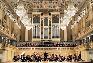 Ein Chor thront über dem Orchester vor einer prunkvollen Orgel. 